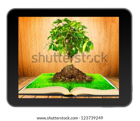 Tree on  open book with grass on wooden planks in black tablet. Concept of growth of knowledge when you read books