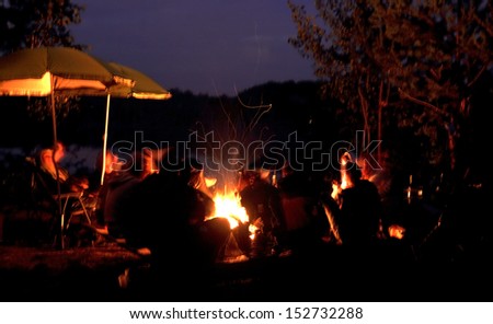 Group of people relaxing near campfire. Blur effect