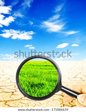 views of the desert with a magnifying glass on a background of green field with a blue sky