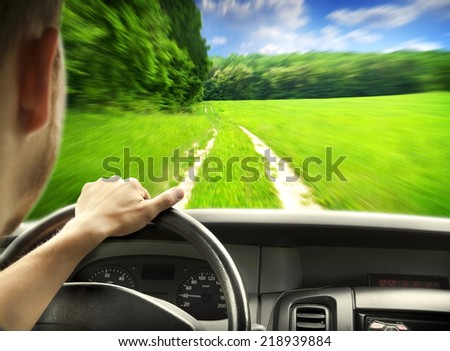 Man\'s hands of a driver on steering wheel of a minivan car on country road