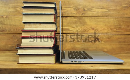 Stack of books and laptop on wooden table