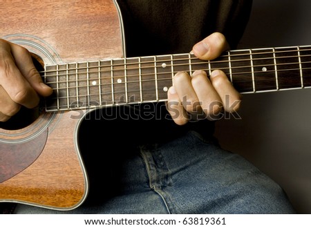 Brown guitar in hands in the guy playing it