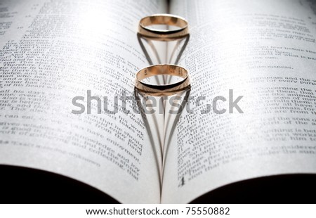 stock photo Wedding rings on a Bible with shadow shape heart