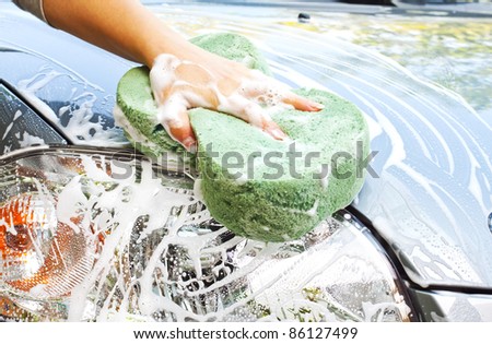 Hand with sponge cleaning car