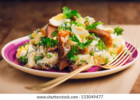 Potato and smoked fish salad with quail eggs, on a vintage table.