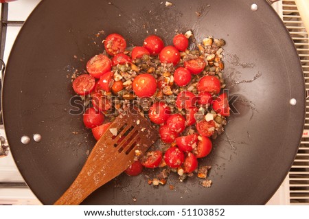 Top view of pasta dressing made of cherry tomatoes in a wok pan.