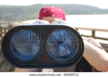 A young man looking at the viewer with a set of binoculars