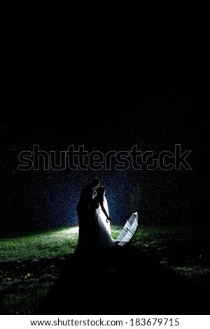Bride and groom in the night rain. Dramatic moment.