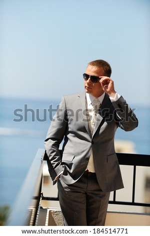 Cool guy with sunglasses standing on a balcony.
