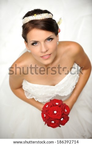 Portrait of a beautiful bride, holding red bouquet of roses.