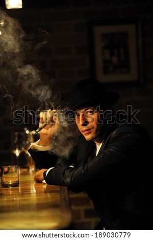 Portrait of a man smoking cigar by the bar. Mafia, retro or gangster style.