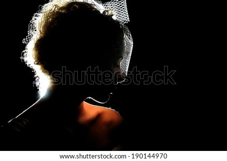 Silhouette of a beautiful bride in the dark background. Retro or vintage style.