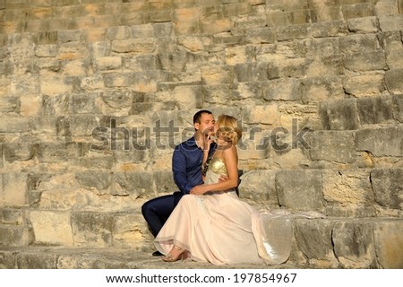 Passionate elegant couple kissing at a beautiful antique Roman amphitheater.
