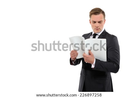 Portrait of a young business man holding and reading journal. Isolated on white background.