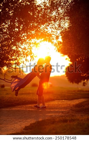 Love couple dancing and kissing in the sunset. Sun flare photo.
