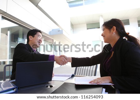 An ethnic man and woman business team handshake at office building