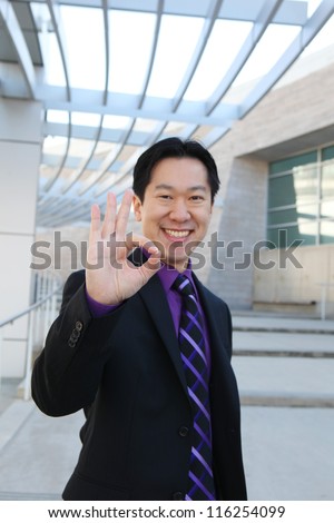 A handsome Chinese business man at office building indicating success (Focus on Hand)