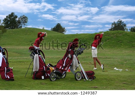 A photo of two school golf team members swinging their clubs