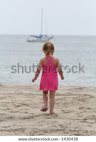 Cute girl in pink walking towards the ocean
