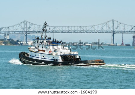 Tug boat in the harbor with a bridge in the background