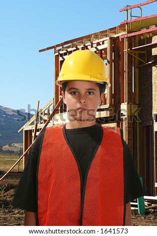 Young construction worker with house in progress in the background