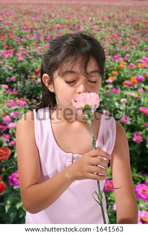 A young girl smelling a flower in a flower garden