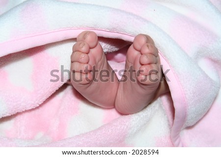 A cute babies feet under a blanket