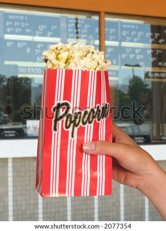 A woman holding a carton of popcorn at the movies