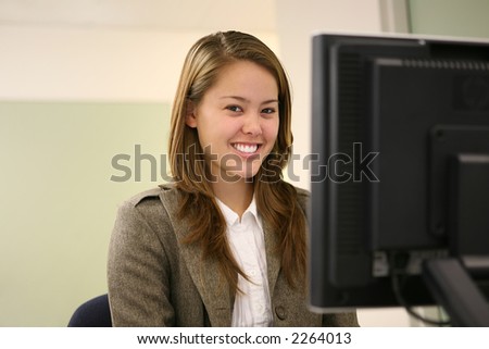 A pretty young woman smiling at the computer