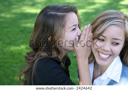 Two teenage women telling secrets in the park