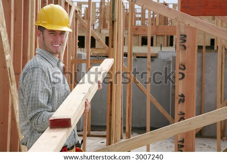 A handsome construction man carrying some wood