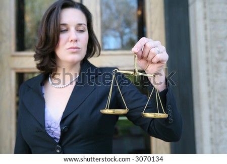 A business woman holding a justice scale outside the court building (Focus on hand with scale)
