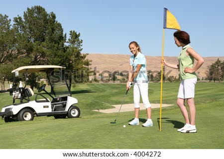 Two pretty young woman golfing on the course