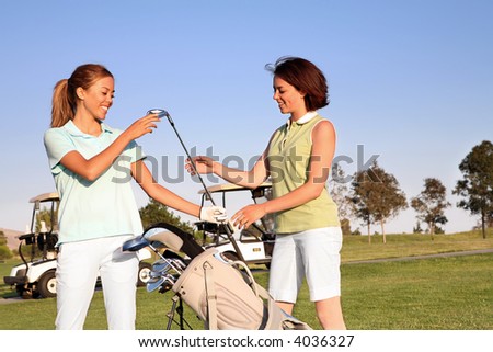 Two pretty women golfers selecting a golf club