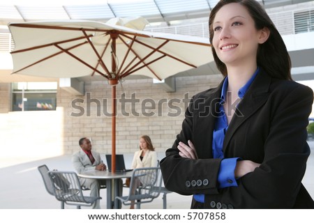 A pretty, young business woman smiling with co-workers in background