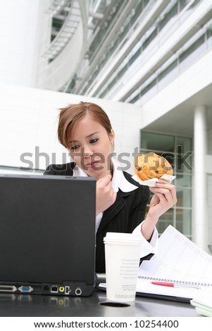 A pretty young woman eating and working on computer