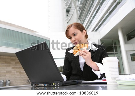 A pretty young woman eating and working on computer