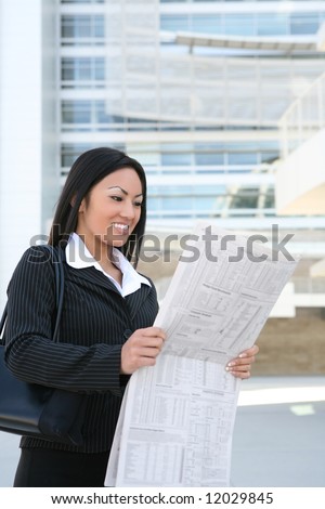 A pretty asian business woman reading the newspaper outside company
