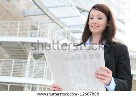 A pretty business woman reading the newspaper outside company