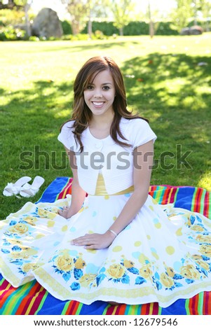A pretty, young girl relaxing in the shade under a tree in the park