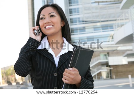 A pretty asian business woman on the cell phone outside office building