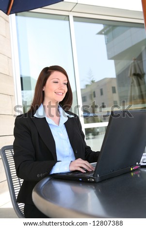 A beautiful young business woman on laptop at office building