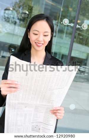Pretty asian business woman reading the newspaper outside office building