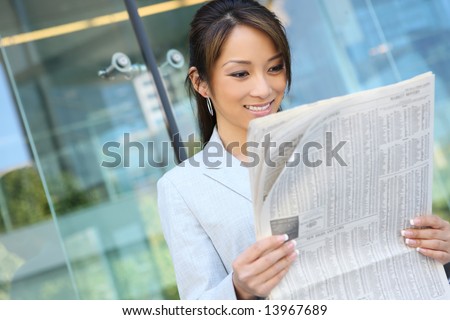 A pretty asian business woman reading the newspaper at office building