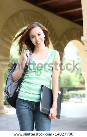 A cute young woman walking to class on university campus