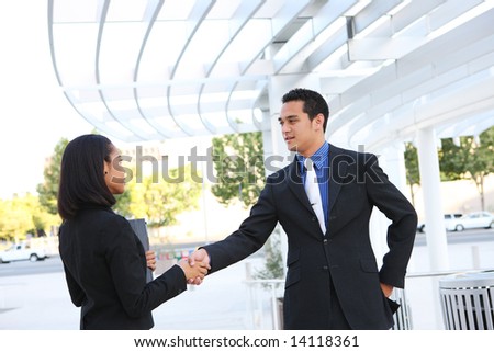 Attractive man and woman business team shaking hands at office building