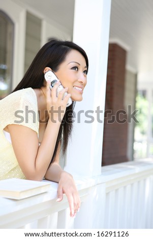 A pretty young woman on the cell phone on her home porch