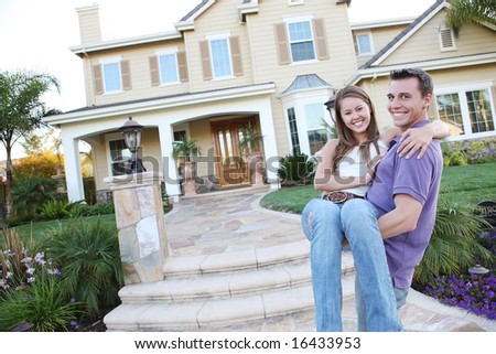 A young man and woman couple in love in front of their new home