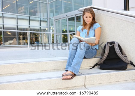 Attractive young woman at school library holding book reading