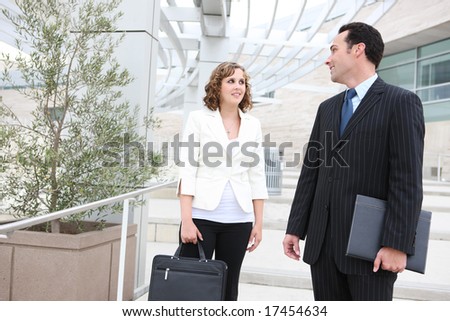 An attractive man and woman business team outside office building